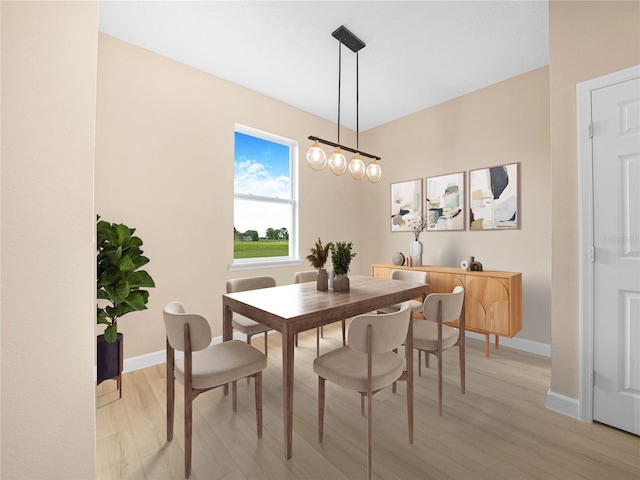 dining space featuring light wood-type flooring and baseboards