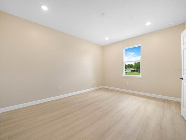 empty room with light wood-style flooring, baseboards, and recessed lighting