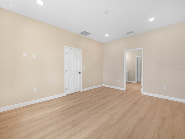 unfurnished room featuring light wood finished floors, visible vents, and baseboards