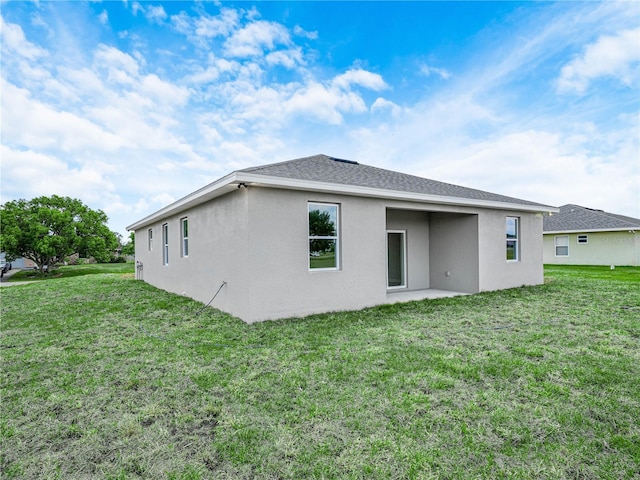 rear view of property featuring a patio, stucco siding, and a lawn