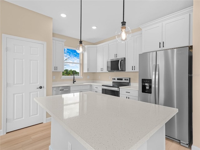 kitchen featuring a sink, stainless steel appliances, pendant lighting, a center island, and light stone countertops