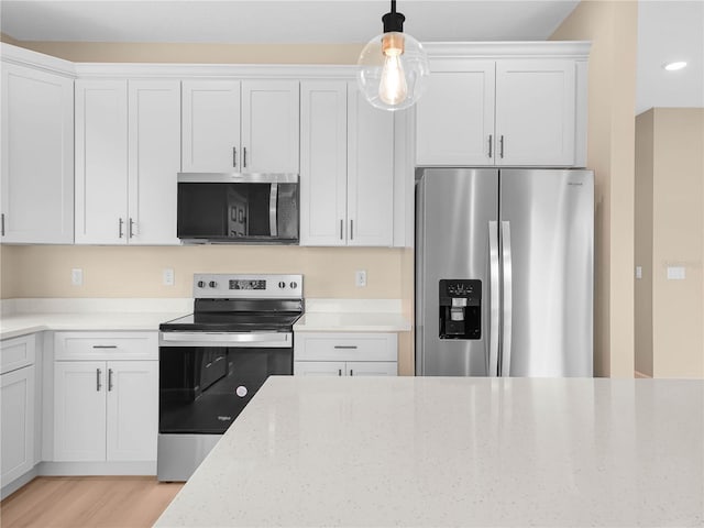 kitchen featuring appliances with stainless steel finishes, light stone counters, pendant lighting, and white cabinetry