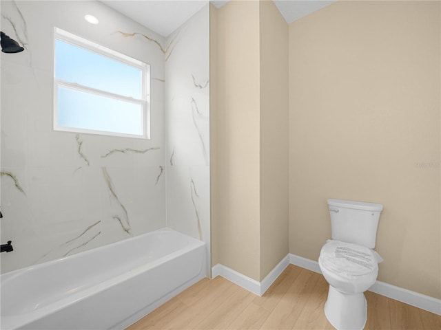 bathroom featuring wood finished floors, toilet, tub / shower combination, and baseboards