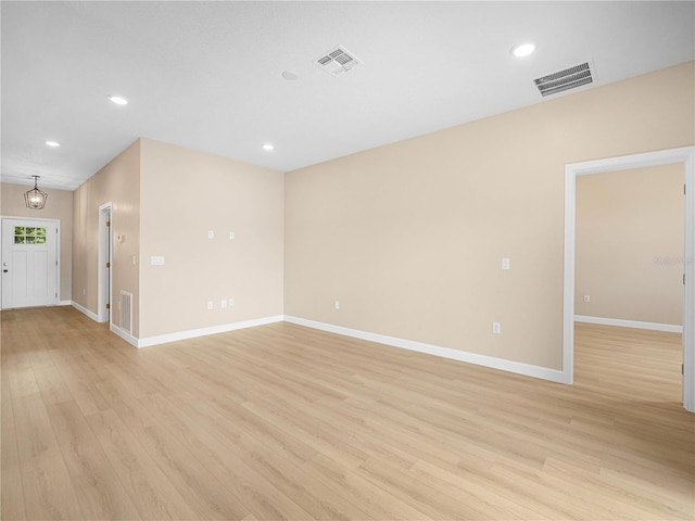 spare room featuring light wood-type flooring, visible vents, baseboards, and recessed lighting