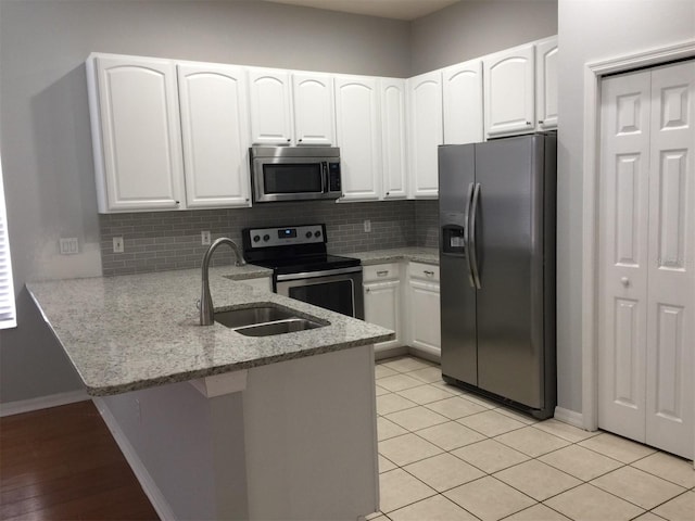 7508 Lake Marsha Dr, Orlando, FL 32819 - kitchen featuring light stone counters, a sink, stainless steel appliances, white cabinetry, and a peninsula
