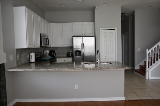 7508 Lake Marsha Dr, Orlando, FL 32819 - kitchen featuring light stone countertops, appliances with stainless steel finishes, a sink, a peninsula, and tasteful backsplash