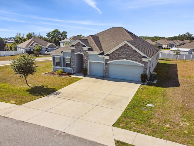 view of front of house featuring a front yard, a residential view, concrete driveway, an attached garage, and stone siding