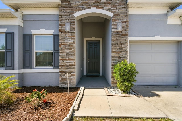 property entrance featuring a garage, stone siding, and stucco siding