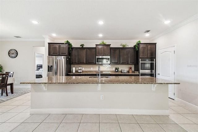 kitchen featuring a kitchen breakfast bar, appliances with stainless steel finishes, a center island with sink, a sink, and light tile patterned floors