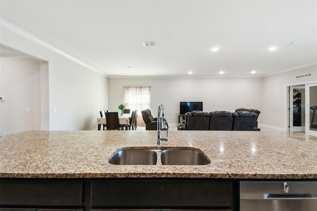 kitchen featuring visible vents, a sink, crown molding, and open floor plan