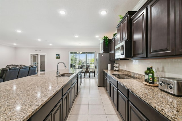 kitchen with ornamental molding, light tile patterned flooring, light stone counters, a sink, and appliances with stainless steel finishes