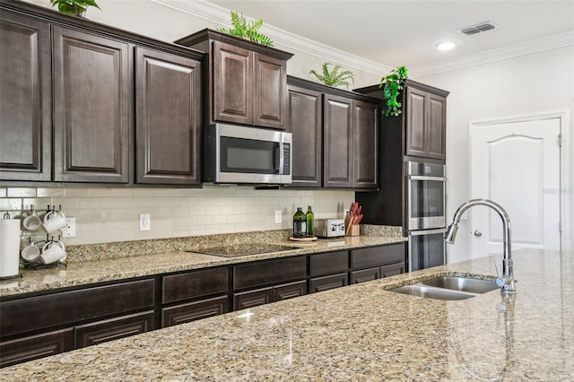 kitchen with light stone counters, a sink, stainless steel appliances, backsplash, and visible vents