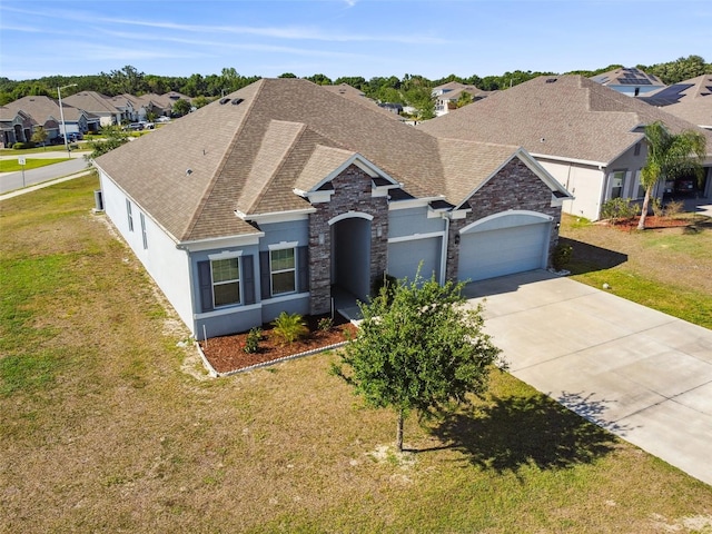 ranch-style home with stucco siding, a shingled roof, stone siding, and a garage