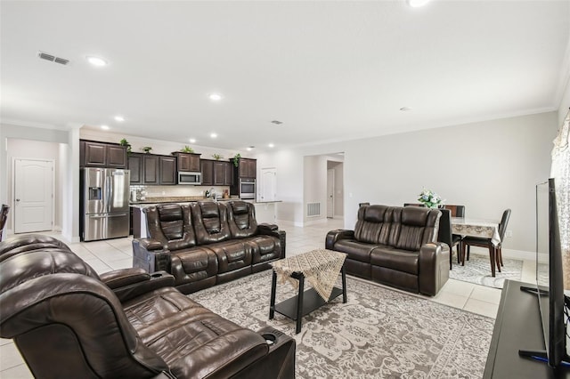 living room featuring crown molding, baseboards, visible vents, and light tile patterned floors