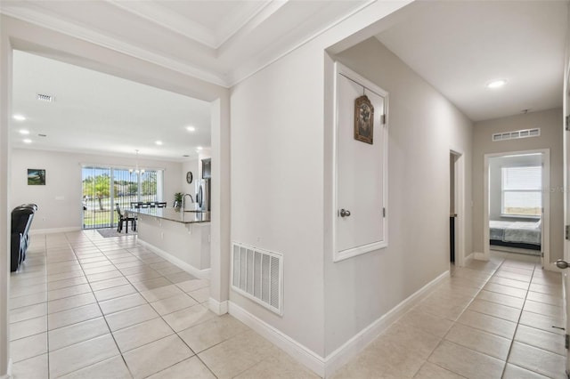 corridor featuring visible vents, baseboards, and light tile patterned floors