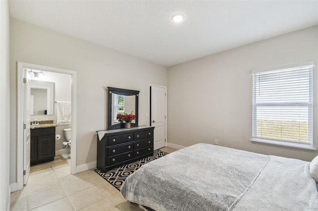 bedroom featuring baseboards, light tile patterned floors, and ensuite bath