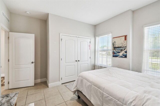 bedroom featuring visible vents, baseboards, light tile patterned floors, and a closet