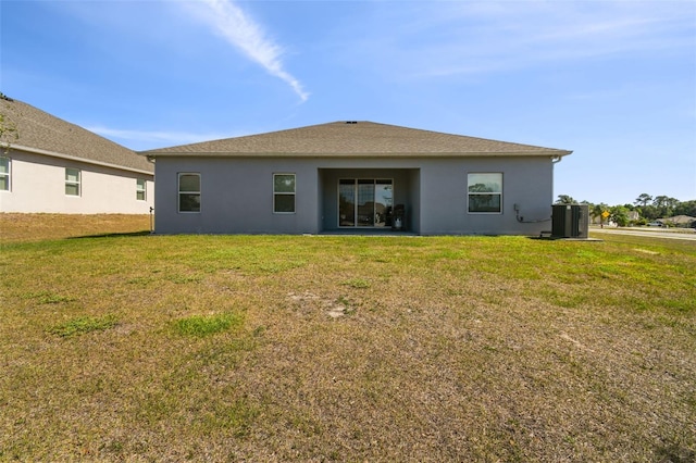 rear view of property featuring a lawn and stucco siding