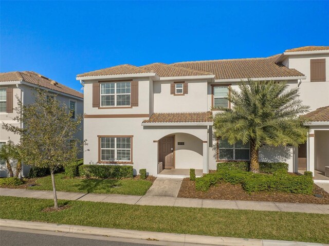 view of front of home with a front lawn, stucco siding, and a tiled roof