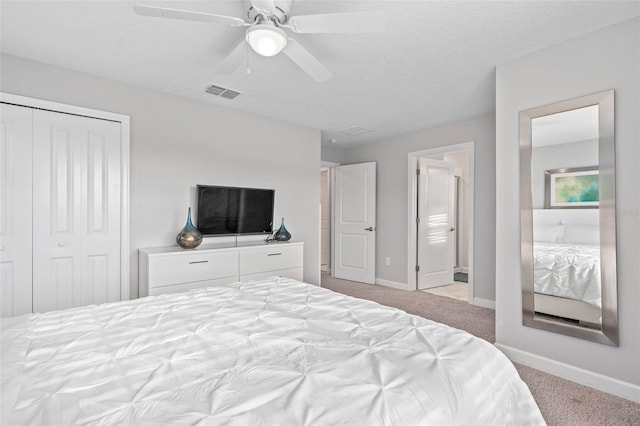 carpeted bedroom featuring a ceiling fan, baseboards, visible vents, and ensuite bathroom