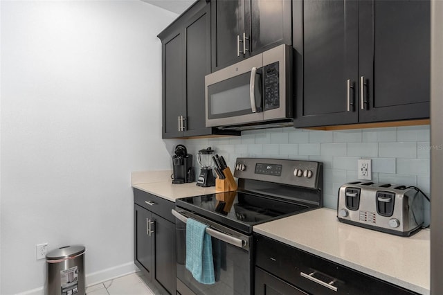 kitchen with baseboards, backsplash, dark cabinets, and stainless steel appliances
