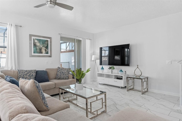 living room featuring baseboards, ceiling fan, a textured ceiling, and marble finish floor