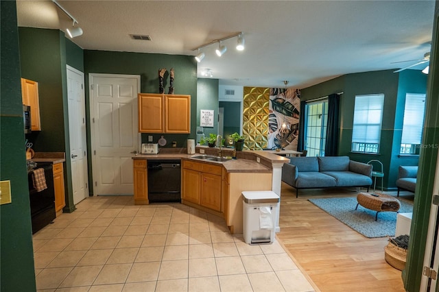 kitchen featuring a sink, rail lighting, a peninsula, open floor plan, and black appliances