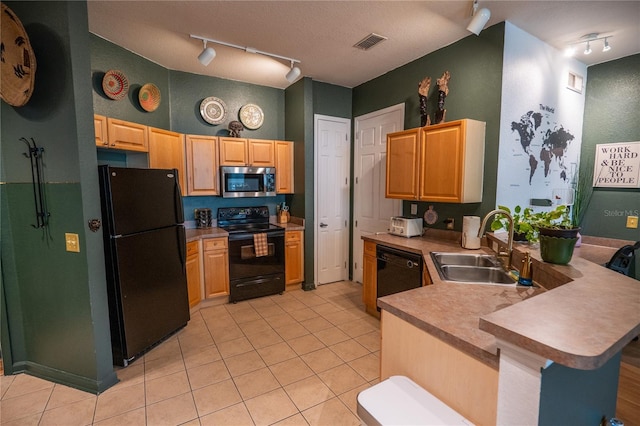 kitchen with a sink, track lighting, black appliances, a peninsula, and light tile patterned flooring