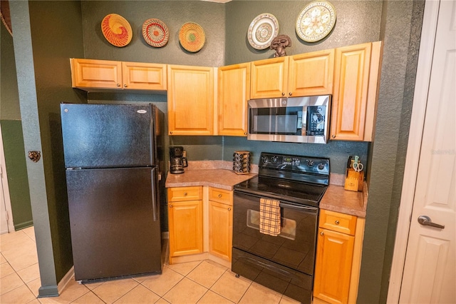 kitchen with a textured wall, light tile patterned floors, and black appliances
