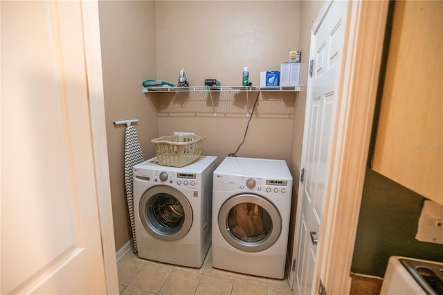 washroom featuring separate washer and dryer, laundry area, and light tile patterned floors