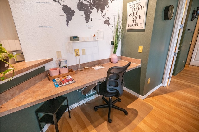 office area with baseboards, a textured wall, wood finished floors, and built in study area