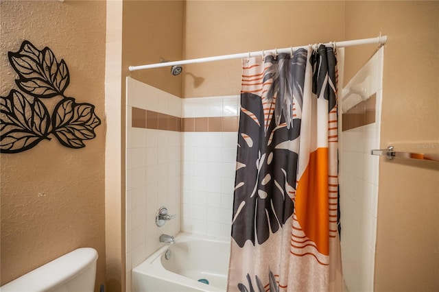 full bathroom with a textured wall, shower / bath combo with shower curtain, and toilet
