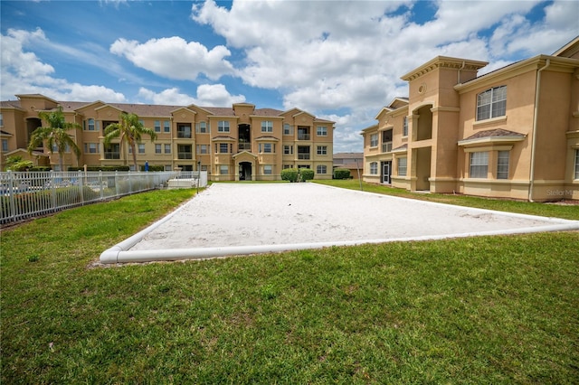 view of community featuring a yard, fence, a residential view, and volleyball court