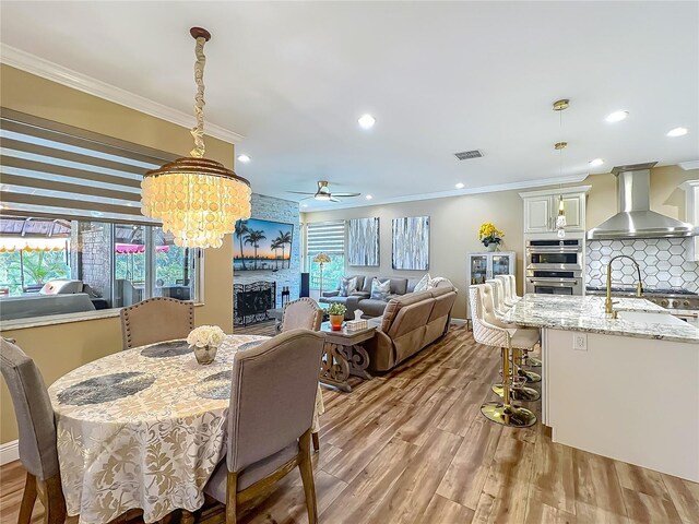 3008 Sutton Woods Dr, Plant City, FL 33566 - dining area with crown molding, visible vents, light wood-style flooring, and ceiling fan with notable chandelier