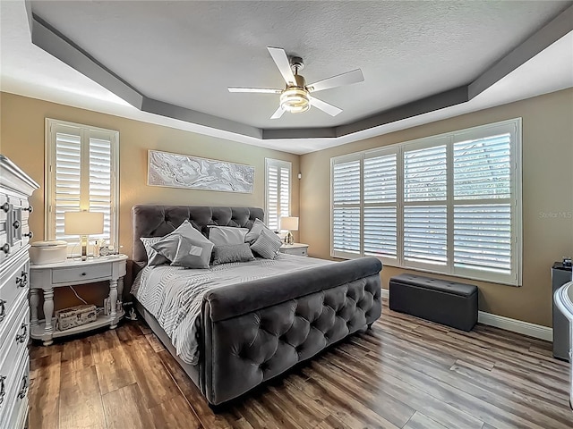 3008 Sutton Woods Dr, Plant City, FL 33566 - bedroom with baseboards, ceiling fan, wood finished floors, and a tray ceiling