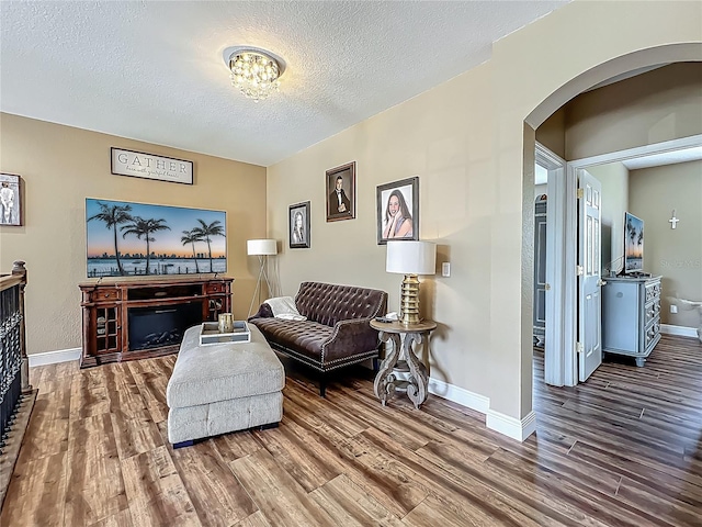 3008 Sutton Woods Dr, Plant City, FL 33566 - living room featuring baseboards, arched walkways, a textured ceiling, and wood finished floors