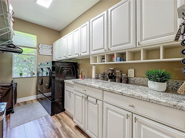 3008 Sutton Woods Dr, Plant City, FL 33566 - clothes washing area with light wood finished floors, baseboards, a sink, cabinet space, and independent washer and dryer