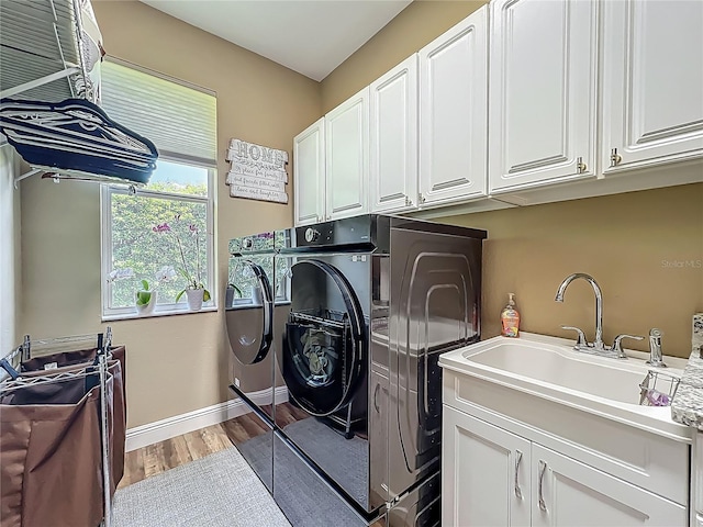 3008 Sutton Woods Dr, Plant City, FL 33566 - laundry area featuring cabinet space, a sink, light wood finished floors, baseboards, and washer and clothes dryer