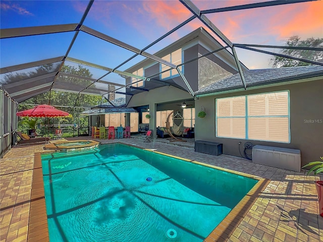 3008 Sutton Woods Dr, Plant City, FL 33566 - pool at dusk with glass enclosure, a pool with connected hot tub, a ceiling fan, and a patio area