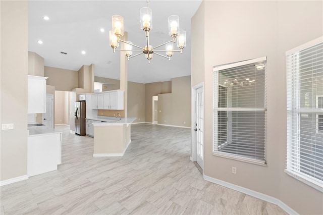 9885 Montclair Cir, Apopka, FL 32703 - kitchen featuring light countertops, stainless steel fridge with ice dispenser, high vaulted ceiling, a chandelier, and white cabinetry