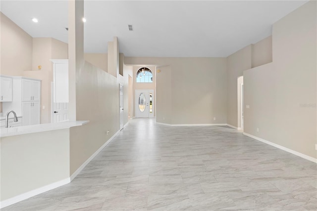 9885 Montclair Cir, Apopka, FL 32703 - unfurnished living room featuring baseboards, a sink, marble finish floor, and a high ceiling