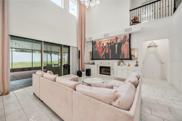 9567 Meadow Hunt Way, Winter Garden, FL 34787 - living area with a glass covered fireplace, a high ceiling, light tile patterned flooring, and a notable chandelier