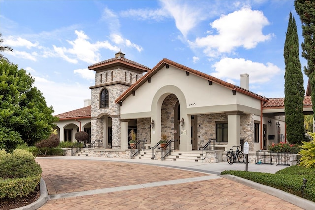 9567 Meadow Hunt Way, Winter Garden, FL 34787 - rear view of property featuring a tiled roof, a chimney, stone siding, and stucco siding