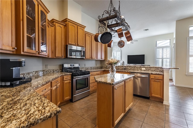 27127 Stoney Brook Dr, Leesburg, FL 34748 - kitchen featuring appliances with stainless steel finishes, a peninsula, light tile patterned flooring, and brown cabinetry