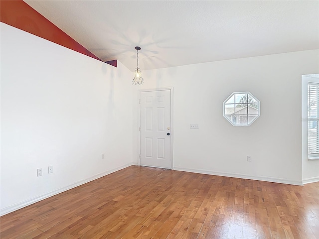 unfurnished dining area featuring baseboards, light wood-style flooring, and lofted ceiling