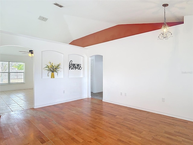 unfurnished room with arched walkways, ceiling fan with notable chandelier, wood finished floors, lofted ceiling, and visible vents