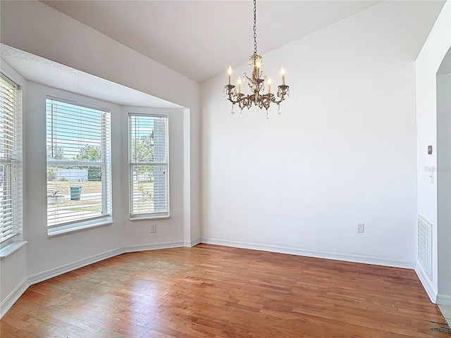 unfurnished dining area with baseboards, an inviting chandelier, and light wood-style flooring