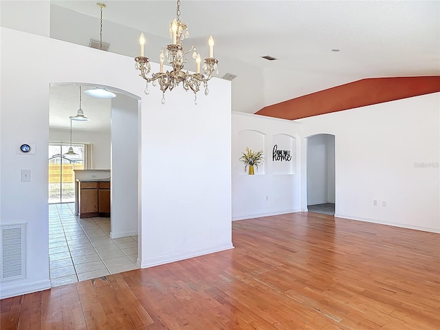 empty room with arched walkways, visible vents, lofted ceiling, and light wood-style floors