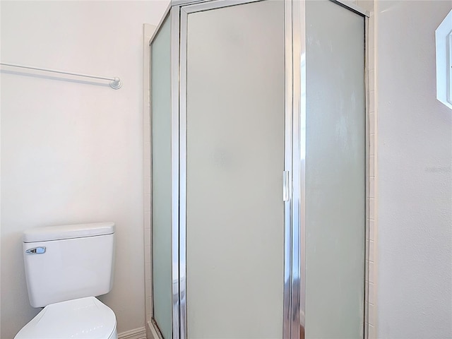 bathroom featuring toilet and a shower stall