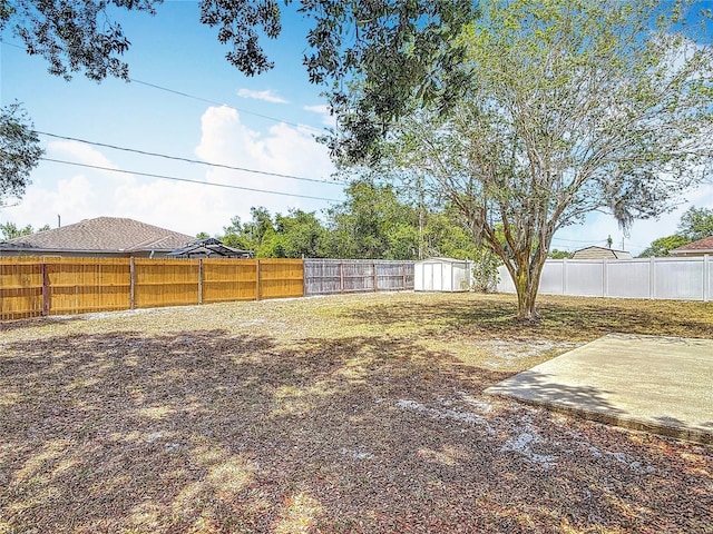 view of yard with a fenced backyard, a shed, and an outbuilding